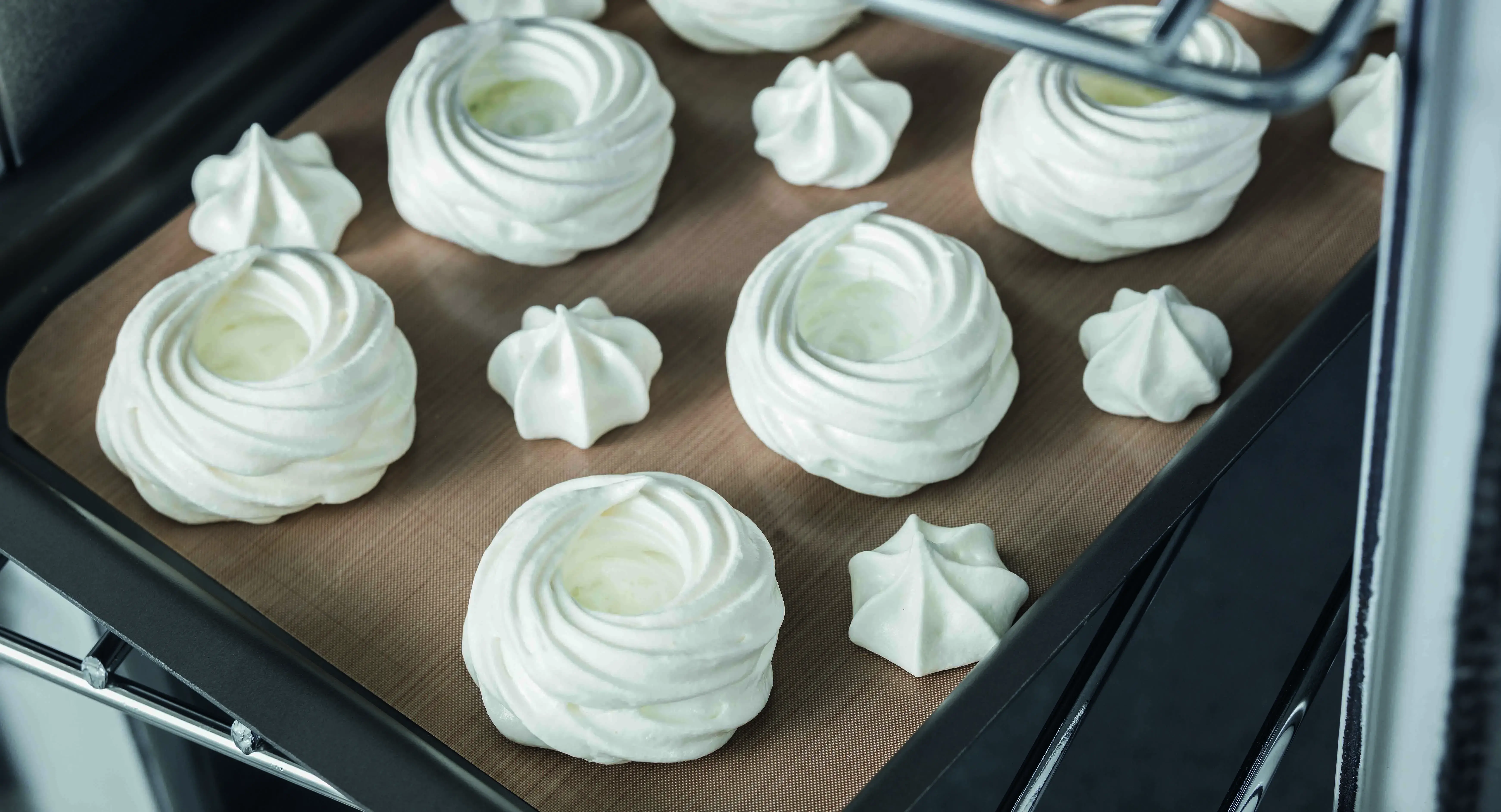 Meringues on baking tray going into oven