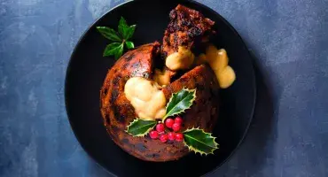 Cheat’s Christmas Pudding with slice cut out of it served with custard