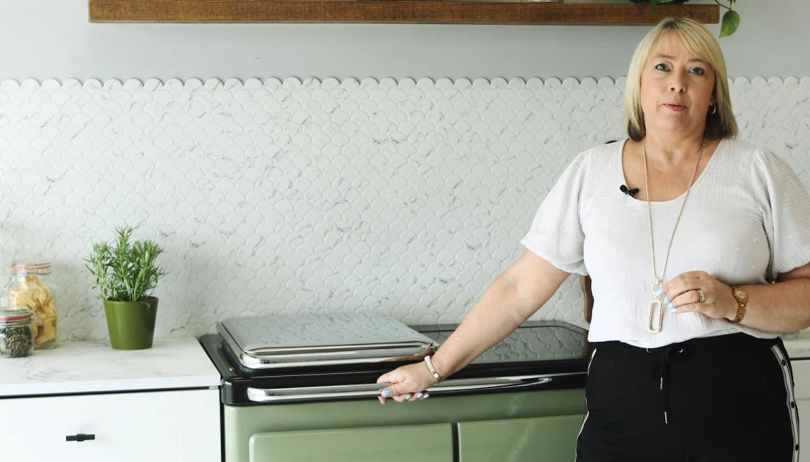 AGA Demonstrator Penny Zako standing next to Rayburn Ranger cooker in Olivine
