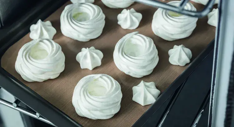Meringues on baking tray going into oven