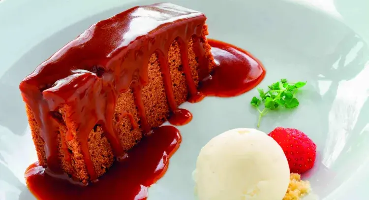Slice of Sticky Toffee Traybake with ice cream and strawberry